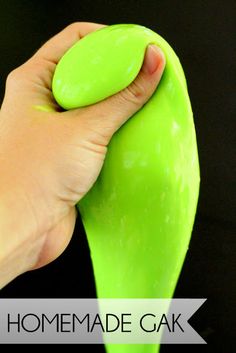 a hand holding a green object in front of a black background