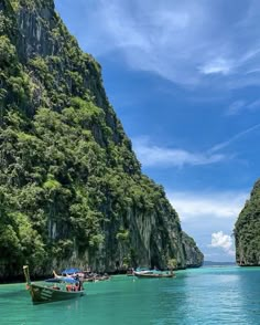 several boats floating on the water in front of some mountains and trees with blue sky