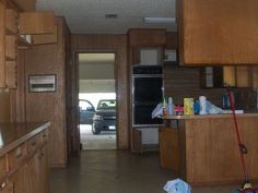 an empty kitchen with wood cabinets and a car parked in the garage door way behind it