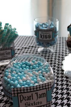 a table topped with blue and white candies next to cupcakes on top of a checkered table cloth