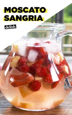 a pitcher filled with fruit sitting on top of a wooden table