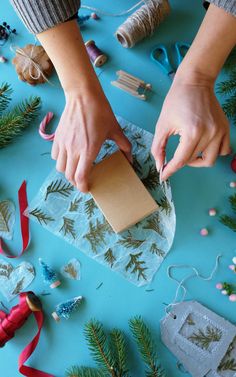 someone is wrapping christmas presents on a blue table with scissors and twine spools