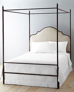 a four poster bed with white sheets and pillows