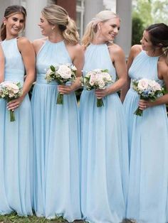 a group of women standing next to each other wearing blue dresses and holding bouquets