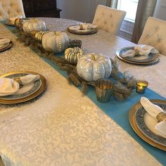 the table is set with silver and gold plates, napkins, and place settings