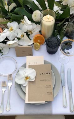 the table is set with white flowers and place settings for an elegant dinner or brunch