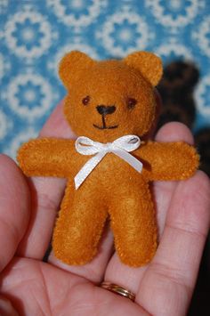 a small brown teddy bear sitting in someones hand