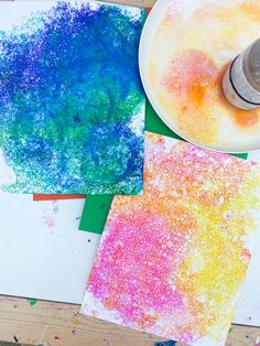 three different colored papers with paint and sprinkles next to each other on a table