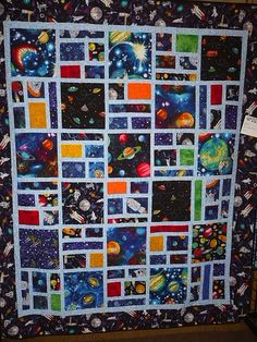 a space themed quilt hanging on a wall