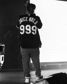 a man standing in front of a stage wearing a black shirt with the words juice wild 999 printed on it