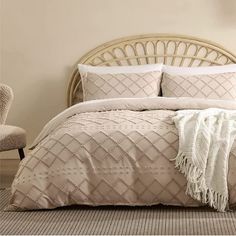 a bed with white pillows and blankets on it next to a wicker headboard