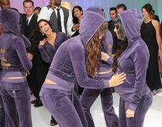 two women dressed in purple are dancing with other people behind them and one woman has her arms around the other