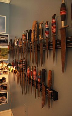 there are many knives hanging on the wall next to each other in front of pictures