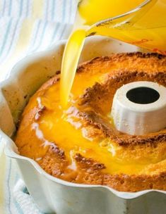 someone pouring orange juice into a cake in a pan