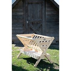 a wooden chair sitting on top of a grass covered field next to a barn door