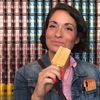 a woman holding a piece of food in front of her face and looking at the camera