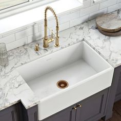 a white kitchen sink sitting on top of a counter next to a faucet