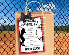 a paper bag with a baseball survival kit on it sitting in front of a fence