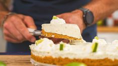 a man is cutting into a cake with a knife and some limes on the table