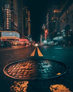 a manhole cover in the middle of a city street at night with neon lights