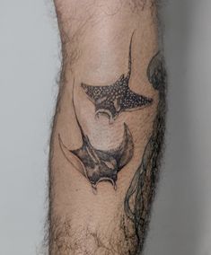 a man with a tattoo on his leg that has a stingfish and waves coming out of it