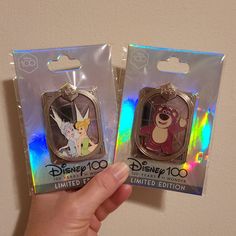 someone is holding two disney keychains in their hand and they are both inside the package