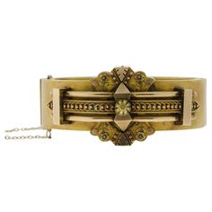 This striking multidimensional Victorian wide hinged bangle bracelet derives from the late nineteenth century. Handcrafted in 14 kt yellow gold and embellished with a classic Etruscan design. Applied goldwork covers the top of this bracelet, featuring engraved and applied gold foliates and dot-work lay on top of a vast, solid, hinged bangle. A straightforward gold safety chain is attached to the bracelet. Measures Approximately 6 1/2" Length by 1 3/16" Width (at widest point) Circa 1885 Luxury Victorian Gold Bracelet For Anniversary, Luxury Gold Victorian Cuff Bracelet, Luxury Victorian Gold Cuff Bracelet, Yellow Gold Bangle, Safety Chain, Gold Work, Gold Bangle Bracelet, Gold Bangle, Hinged Bangle