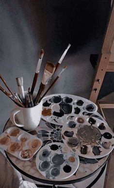 an artist's easel with paint brushes and palettes sitting on top of it