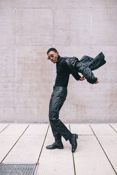 a man in black clothes and sunglasses is doing a handstand