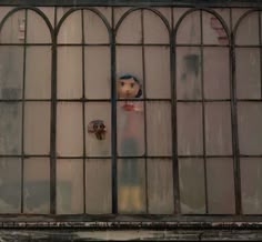 an old window with a doll sticking out of it