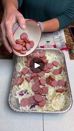 a woman is pouring hotdogs into a pan on the kitchen counter with onions and cabbage