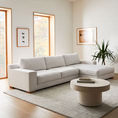 a living room with a large white couch and coffee table in front of two windows