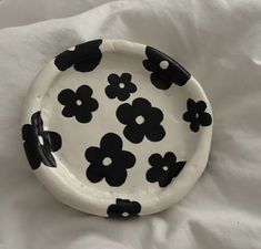 a black and white plate with flowers painted on the side, sitting on a bed