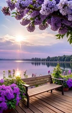 a bench sitting on top of a wooden deck next to purple flowers and trees in front of a body of water