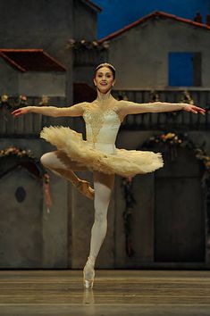 a ballerina in white tutu with her arms outstretched