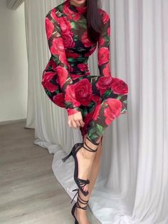 a woman is sitting on the floor wearing high heels and a rose print dress with long sleeves