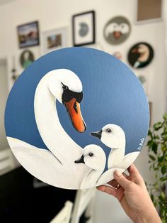 a hand holding up a paper plate with two white swans on it's face