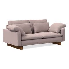 a light pink couch with pillows on it and a wooden frame around the armrests