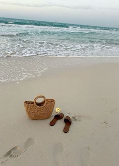 a pair of flip flops sitting on top of a beach next to a basket