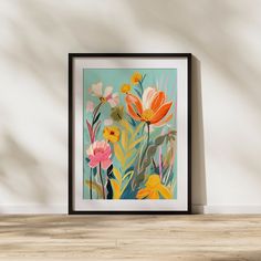 an art print with flowers on a wall above a table in front of a white wall