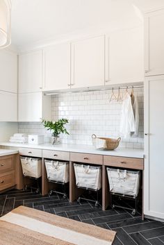 a kitchen with white cabinets and black tile flooring is pictured in this image, there are towels hanging on the rack above the sink