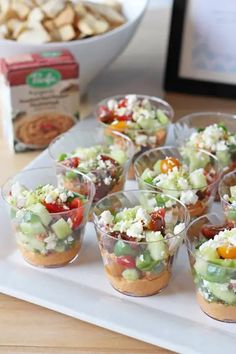 small cups filled with food sitting on top of a white tray next to a box of crackers