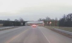 a car driving down a highway with trees in the background