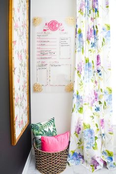 a basket sitting in front of a window next to a wall with flowers on it