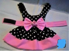 a black and white polka dot dress with pink bow on the front, sitting on top of a bed