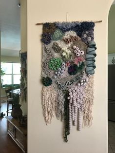 a wall hanging made out of different types of yarns and other things on it