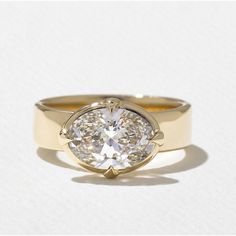 a yellow gold ring with a round diamond in the center, on a white background