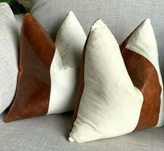 two brown and white pillows sitting on top of a gray couch next to each other