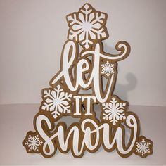 a wooden sign that says let it snow with snowflakes on the top and bottom