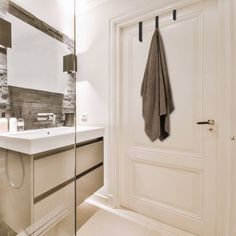 a bathroom with a sink, mirror and towel hanging on the door handle next to it